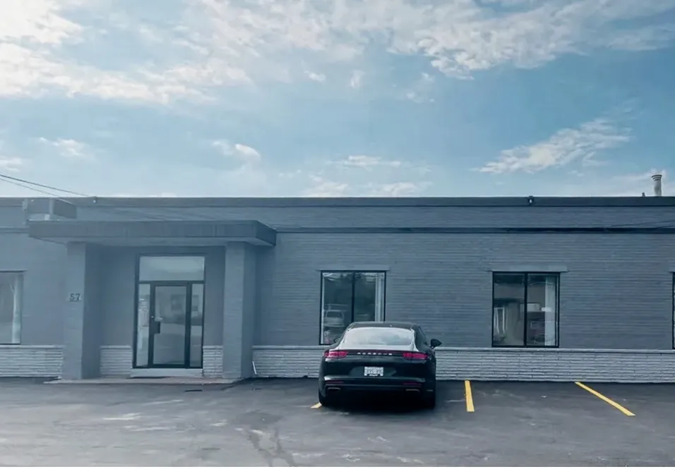 Photo of Mack & Milne: a grey single-storey building numbered 57, with parking.