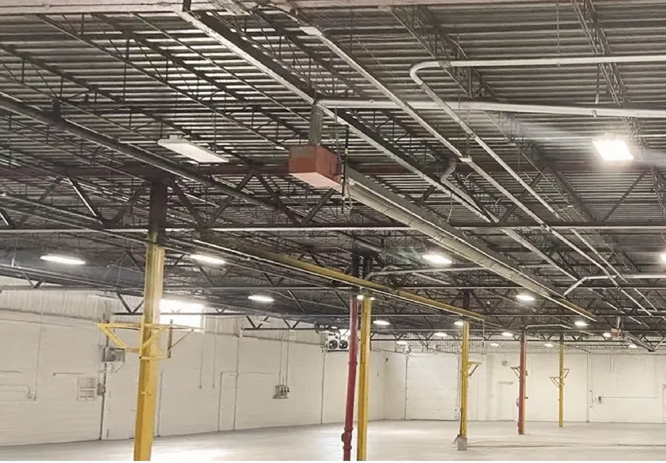 Photo of an empty warehouse interior with steel roof trusses and yellow columns.