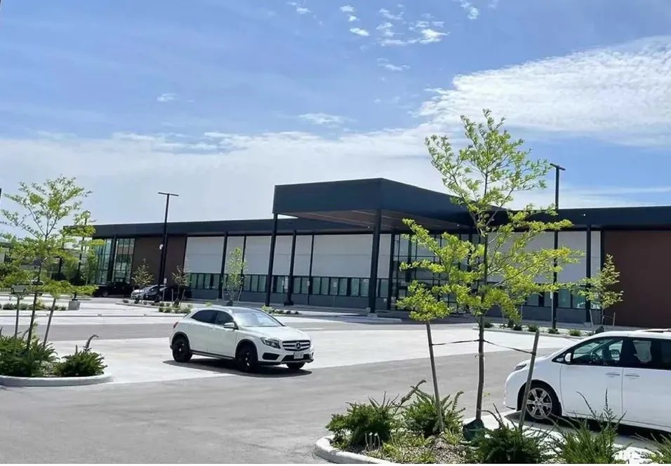 Photo of the commercial building across a parking lot with young trees.
