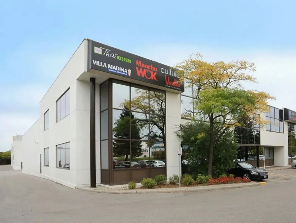 Photo of the building's glazed corner with trees and parked cars.